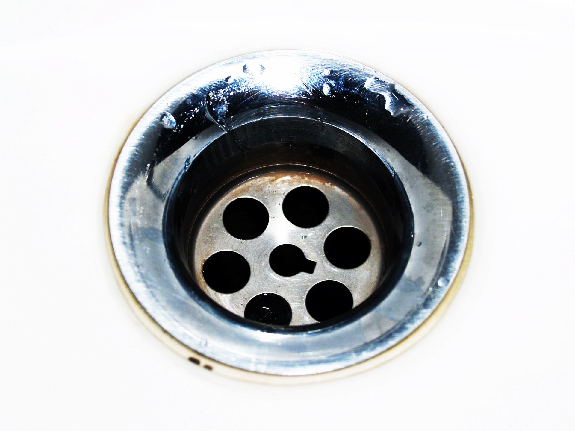Detailed image of a chrome sink drain showcasing water droplets and a metallic finish.