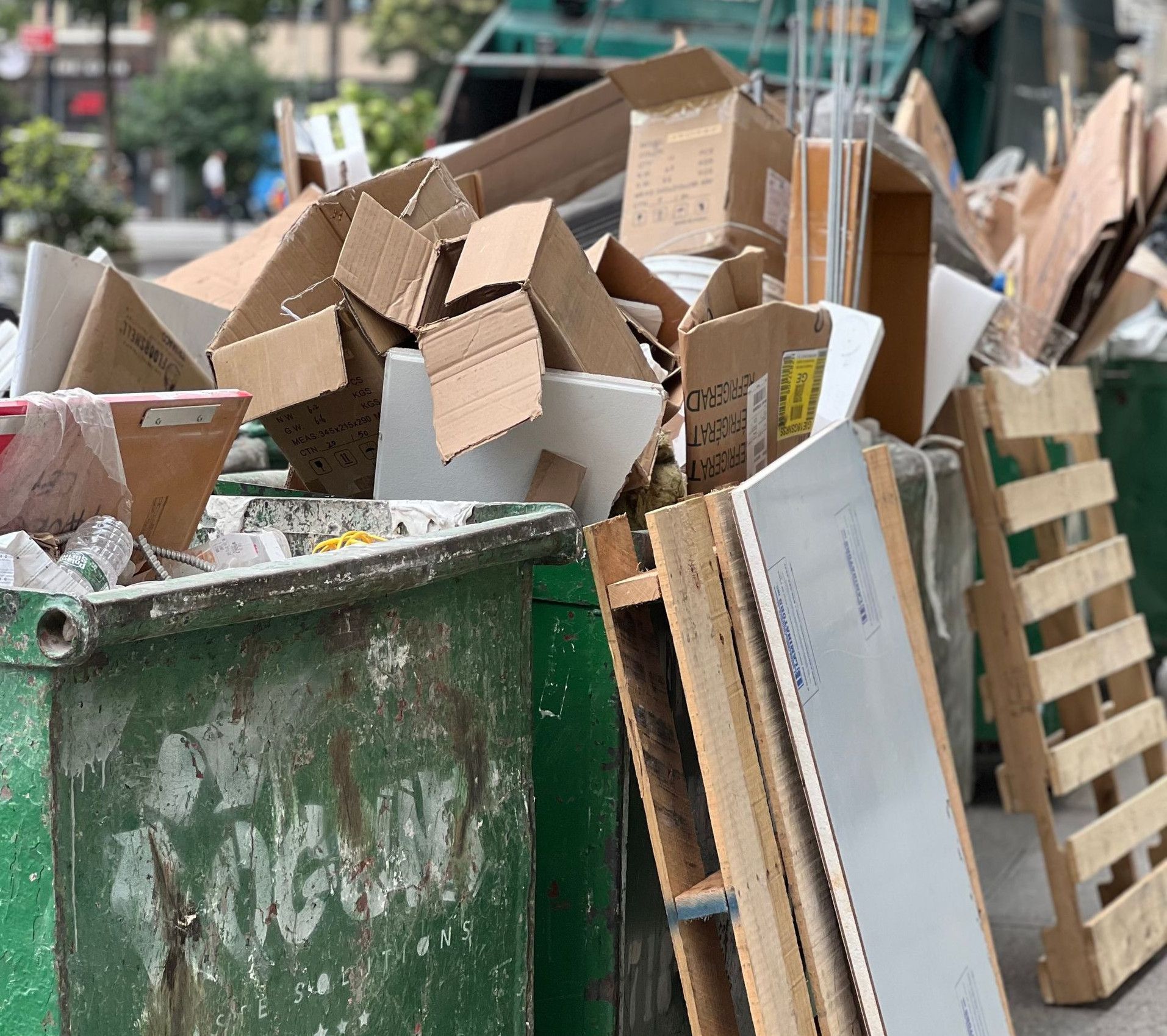 Piled cardboard boxes and waste in a city dumpster highlight urban recycling.