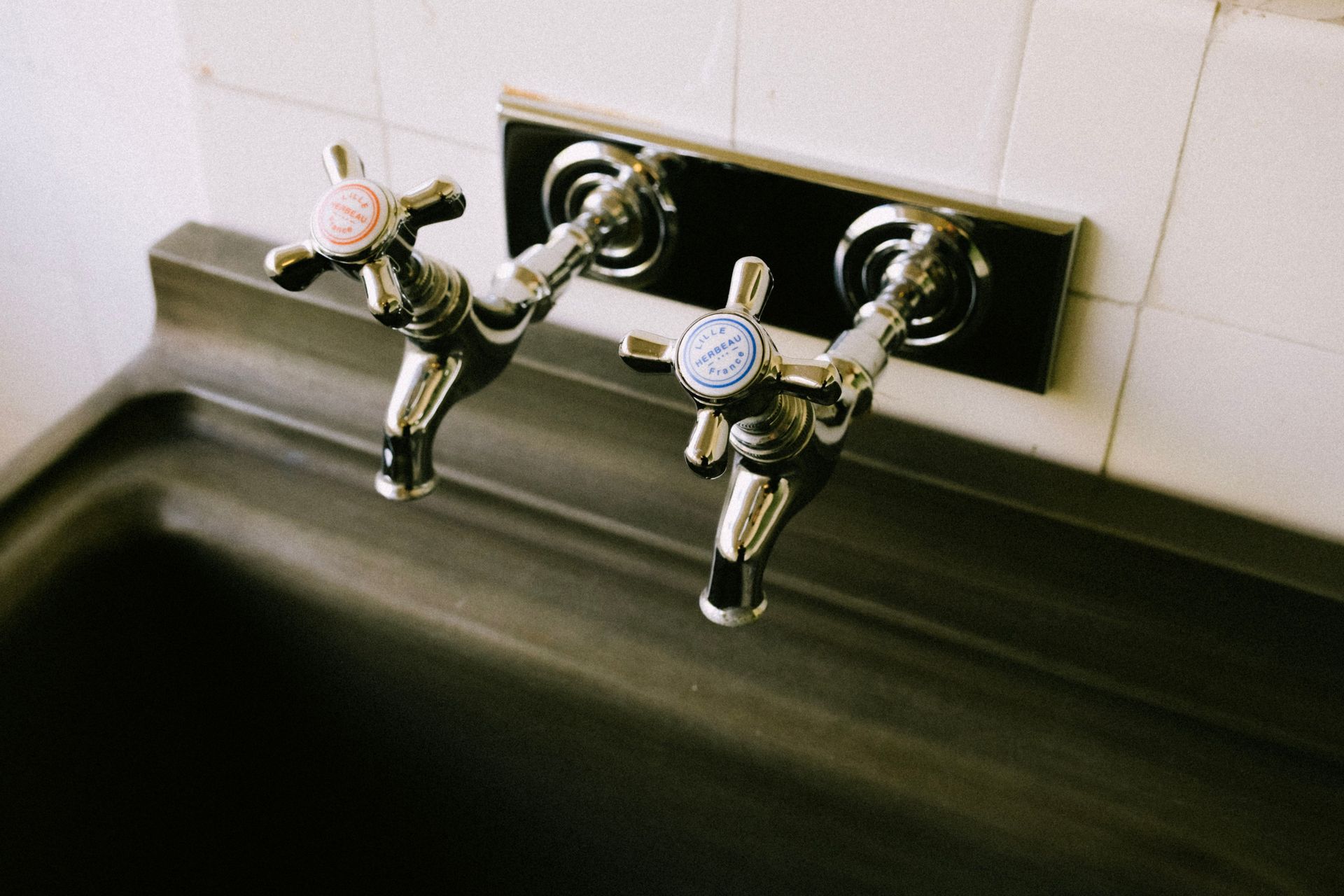 Detailed view of chrome sink faucets with classic hot and cold labels in a kitchen setting.