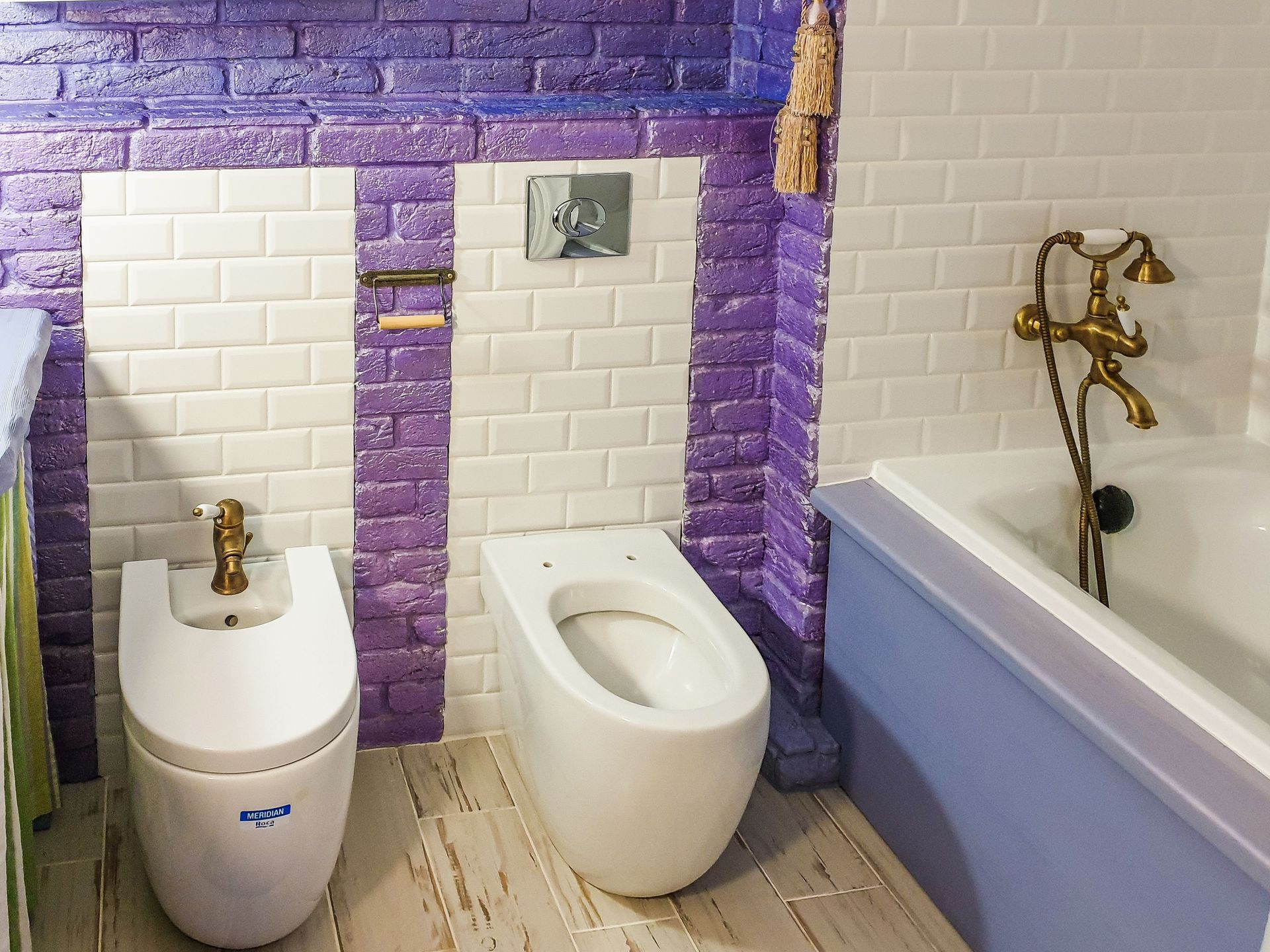 Stylish bathroom featuring a bidet and bathtub with vibrant purple and white tiles.
