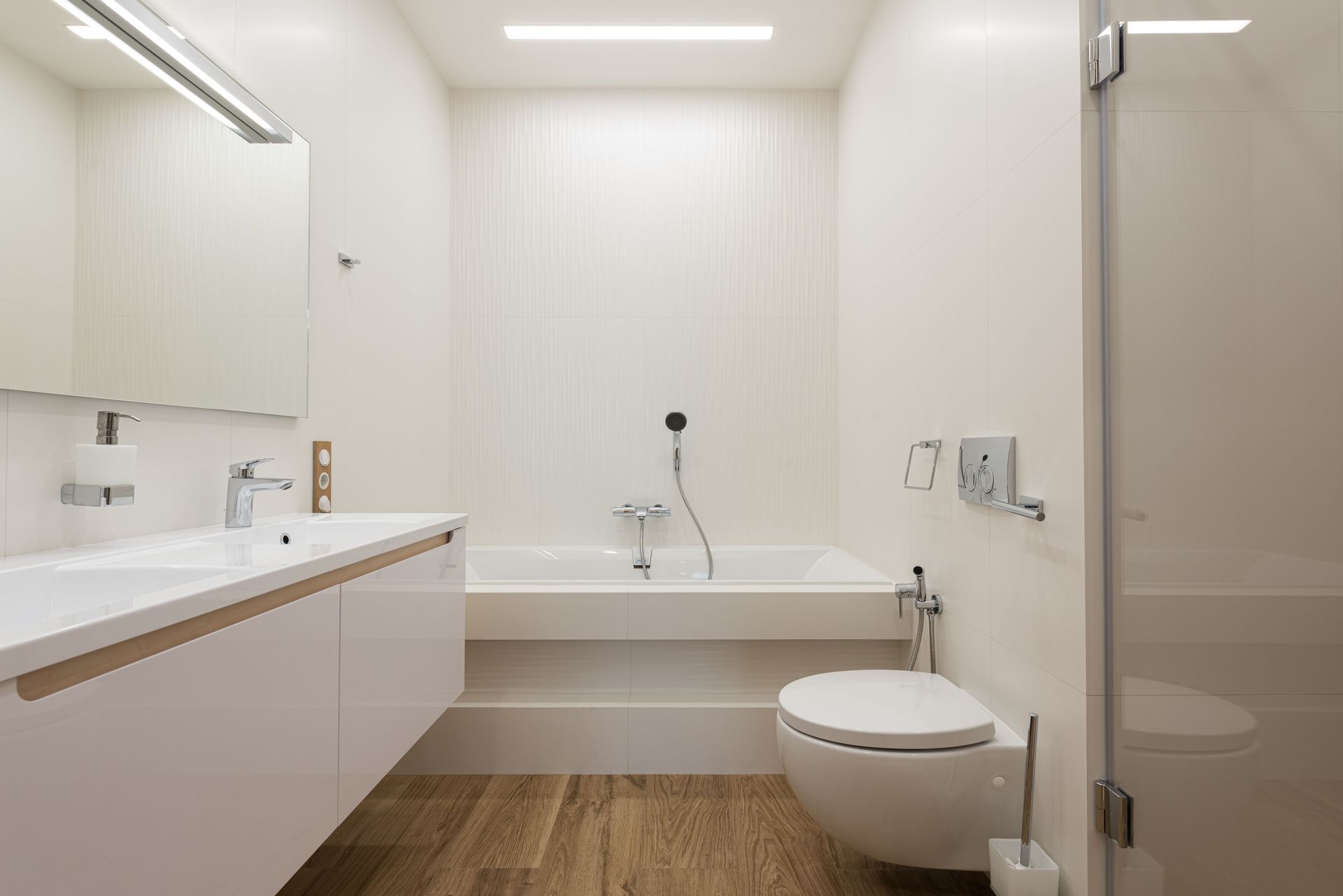 Interior of modern light bathroom with white bathtub and cabinet in front of shower cabin with glass doors