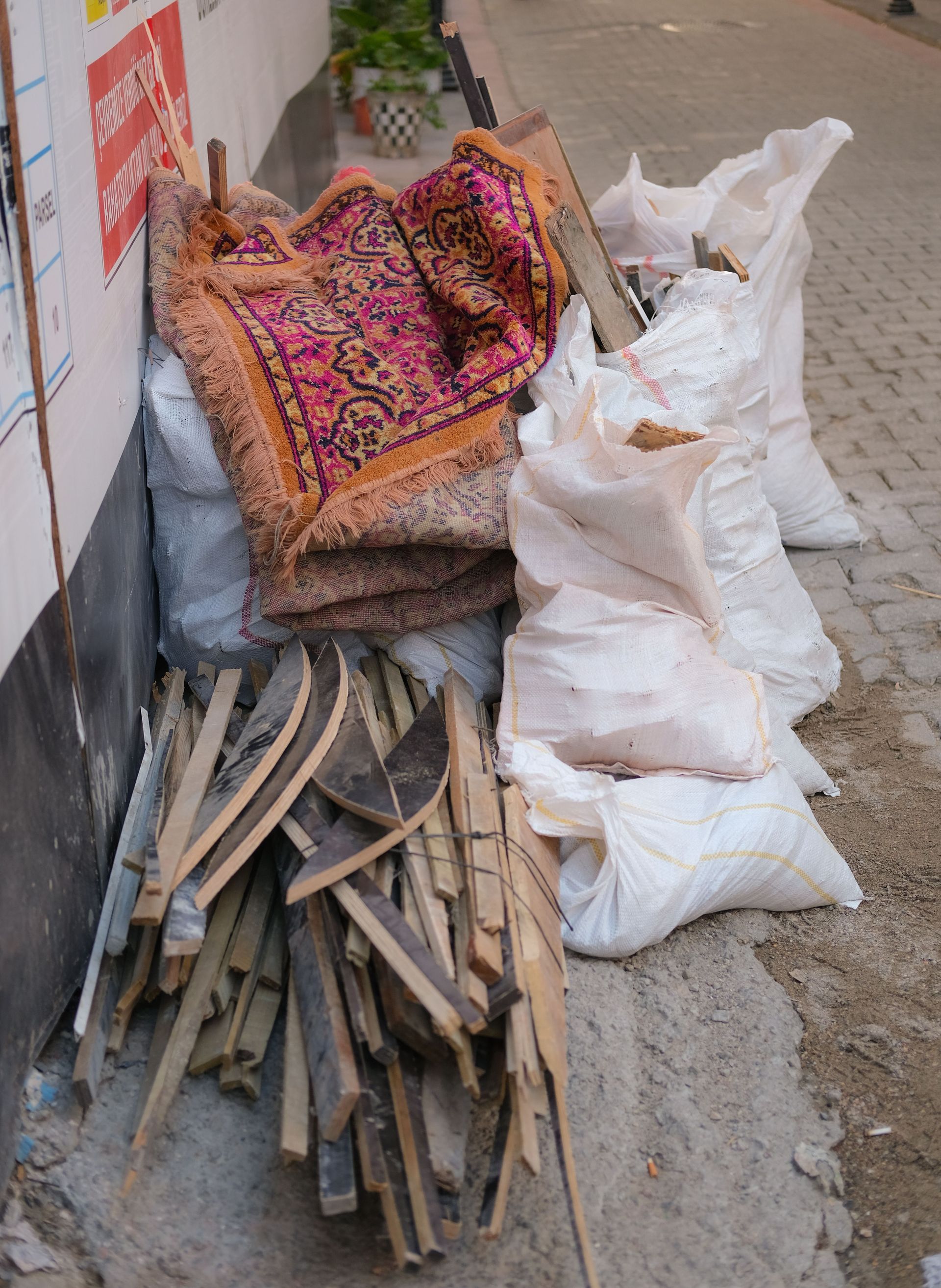 Discarded construction materials on a city street, including wood planks and sacks.